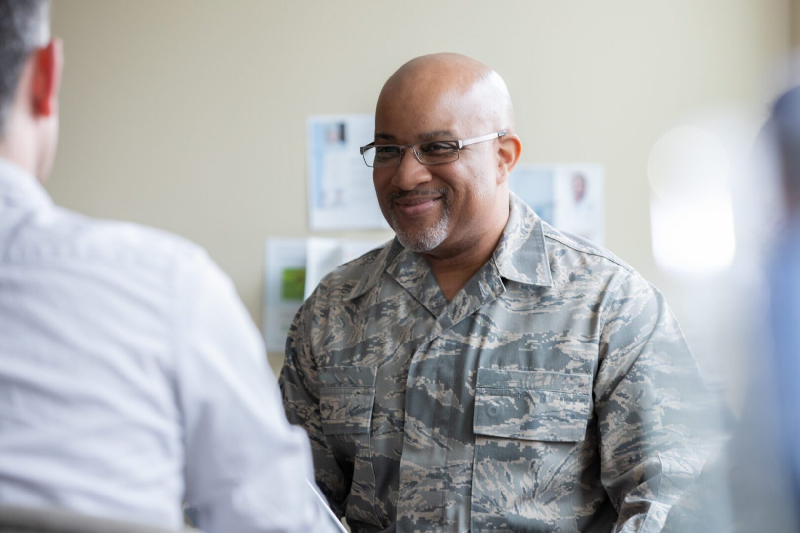 Smiling military officer in camouflage uniform during a conversation.